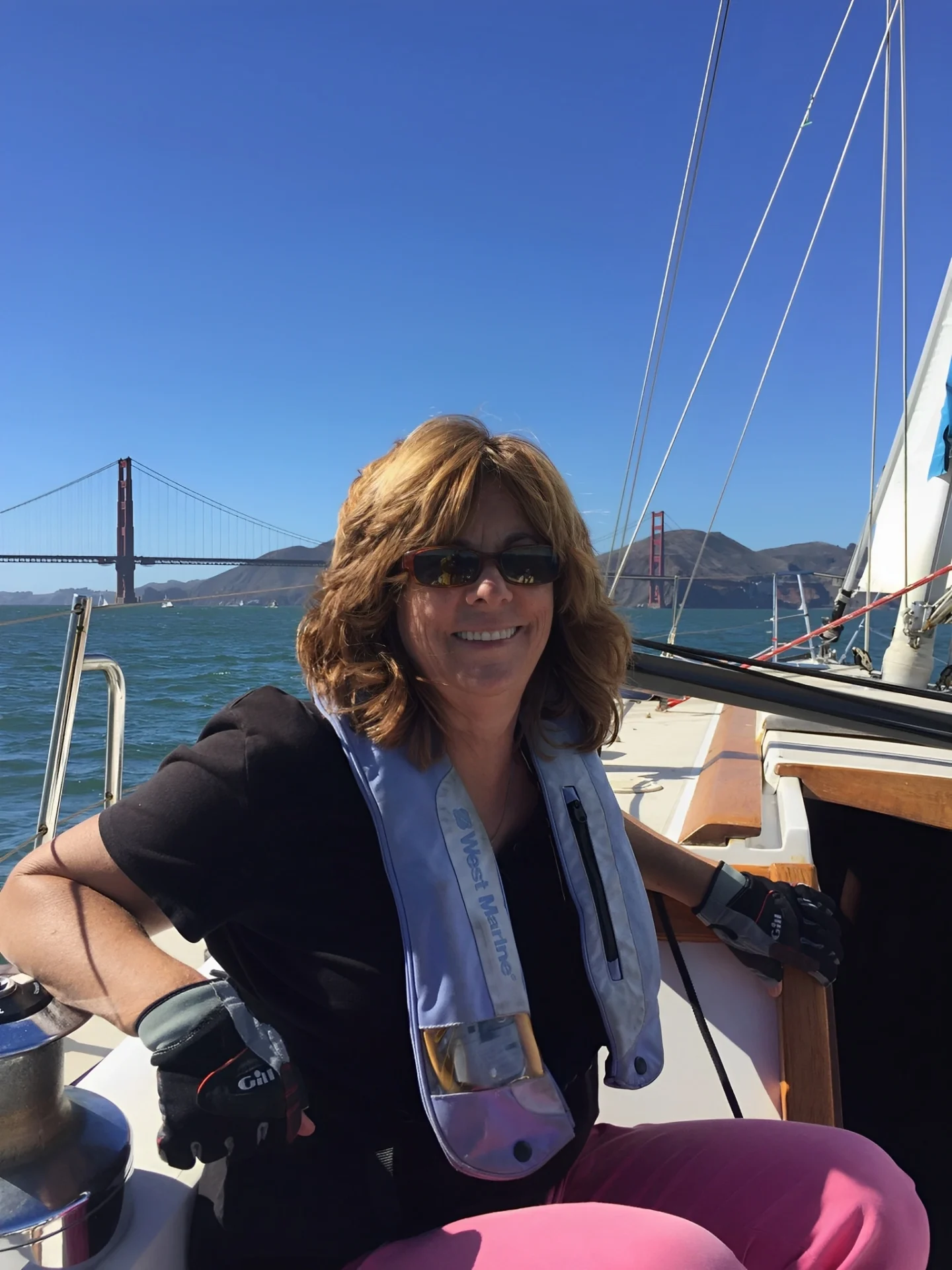 Diana on a sailboat with the Golden Gate Bridge in the background, smiling.